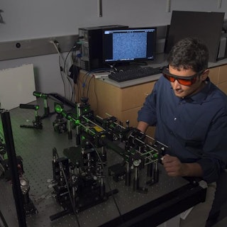 Graduate student in a lab wearing safety eyewear while working with lasers